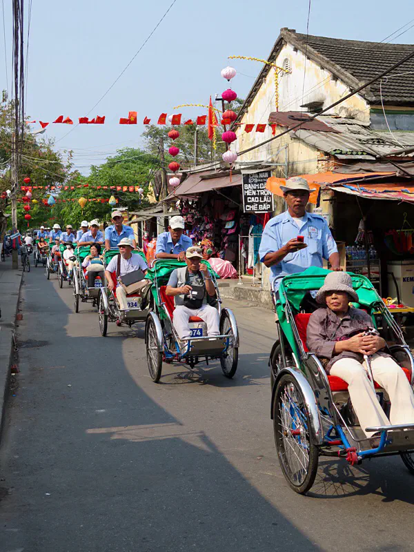 Schlange von Fahrrad-Rikschas mit japanischen Touristen, Hoi An